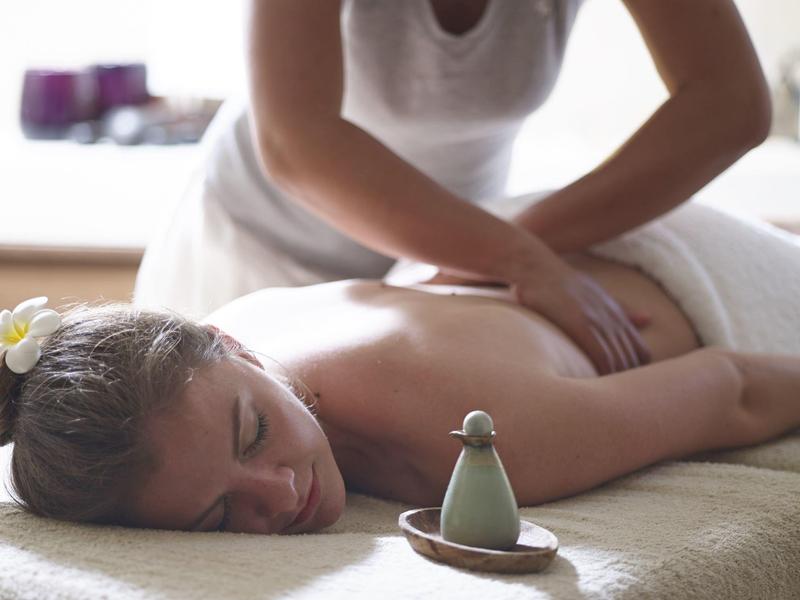 Frau entspannt bei Massage in Spa-Umgebung mit Aromatherapie-Duftöl.