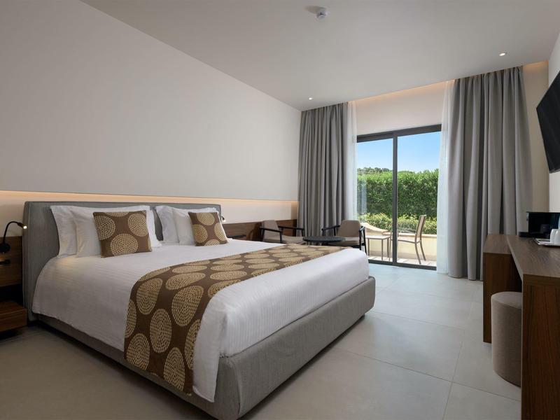 Modernes Hotelzimmer mit Doppelbett, TV, Balkon und minimalistischer Einrichtung.