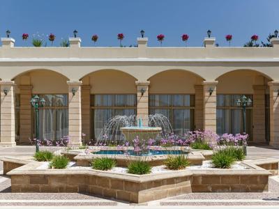 Un cortile elegante con fontana e fiori davanti a un edificio classico.