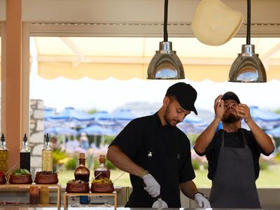 Due cuochi preparano hamburger in un bar sulla spiaggia con vista mare.