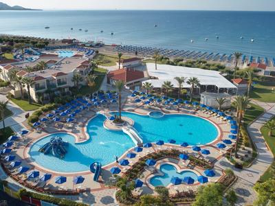 Vista di un hotel con grandi piscine, lettini da sole e accesso diretto al mare.