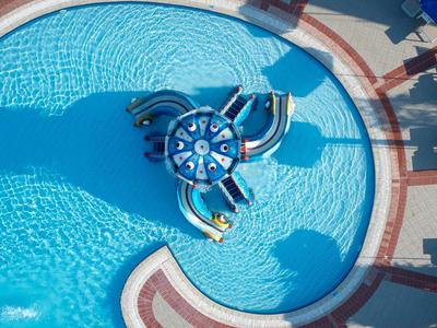 Grande piscina rotonda con gioco colorato e ombrelloni blu