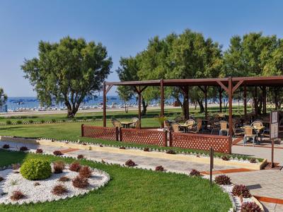 Ogród przypominający park z alejkami, drzewami i miejscem do siedzenia blisko morza.