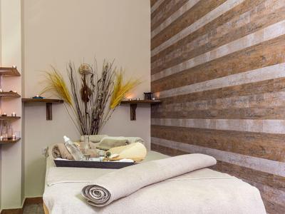 Sala relax con lettino da massaggio, asciugamani piegati e piante decorative.