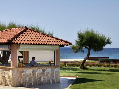 Open beach bar with red tiled roofs overlooking the sea under a clear sky.