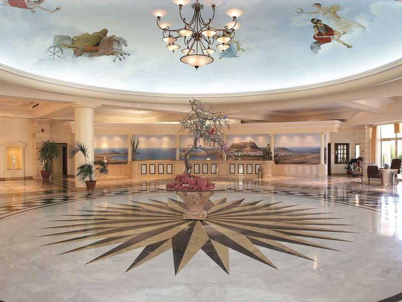 Ampio atrio dell'hotel con motivo artistico sul pavimento e affresco dipinto sul soffitto.