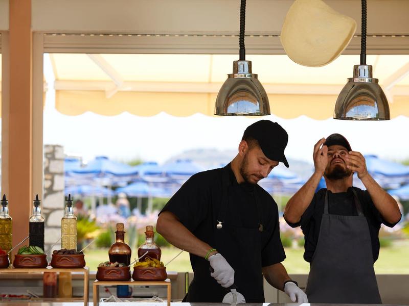 Due cuochi preparano hamburger in un bar sulla spiaggia con vista mare.
