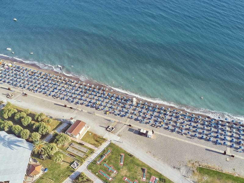 Vista aerea di una spiaggia con file di ombrelloni e costa visibile.