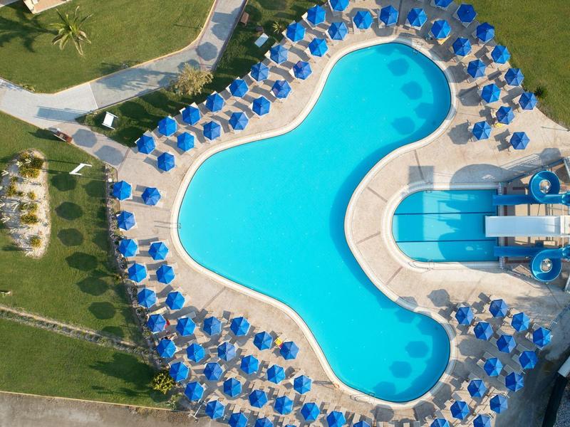 Vista aerea di una piscina circondata da ombrelloni blu in un hotel