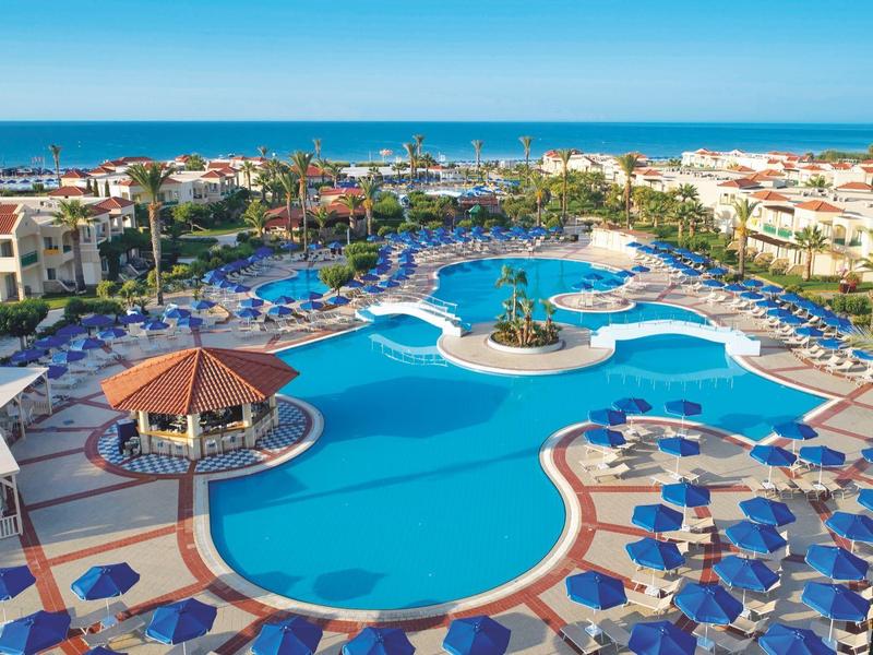 Grande piscina dell'hotel con ombrelloni e vista sul mare sullo sfondo.