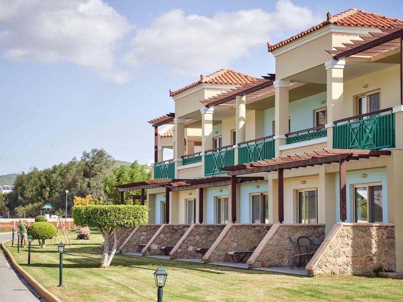 Hotel moderno su due piani con balconi e prato curato sotto un cielo limpido.