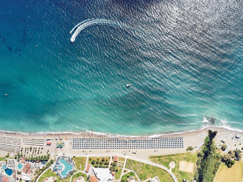 Veduta aerea di una spiaggia con sabbia, acqua blu e una barca con nuotatori