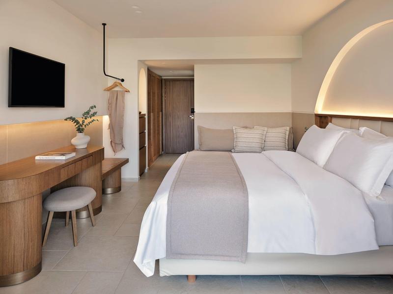 Camera d'hotel moderna con letto grande, scrivania in legno e arredamento minimalista.