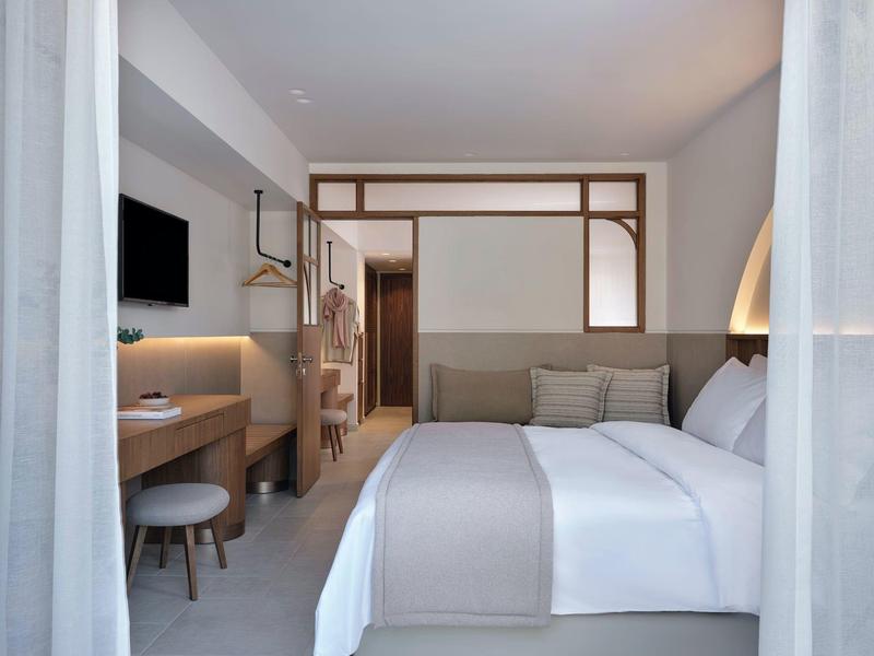 Camera d'hotel moderna con letto grande, scrivania, TV e design luminoso e pulito.