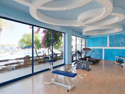 Heller Fitnessraum mit großen Fenstern und Blick auf Terrasse und Außenbereich.