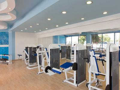 Moderner Fitnessraum mit verschiedenen Trainingsgeräten und großen Fenstern.