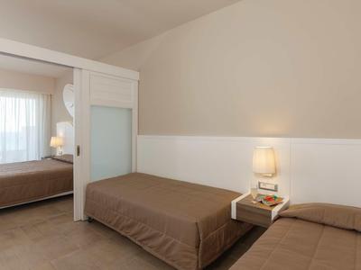 Camera d'hotel moderna con due letti singoli, biancheria marrone e comodino con lampada.