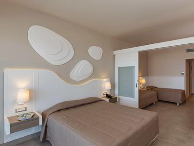 Camera d'hotel moderna con due letti, comodini, lampade e decorazione murale morbida.