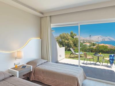 Camera con due letti singoli e vista mare attraverso porte scorrevoli in vetro.