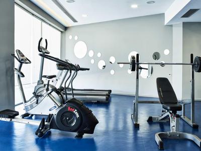 Moderner Fitnessraum mit Trainingsgeräten und großen Fenstern in einem Hotel.