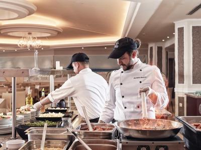 Due chef preparano e cucinano pasti in una cucina d'hotel spaziosa e ben illuminata.