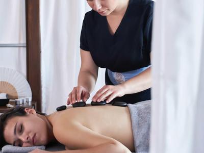 Persona che riceve un massaggio con pietre calde in una tranquilla stanza spa con luce naturale.