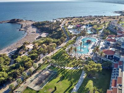 Luftaufnahme eines Resorts am Meer mit Pool, Strand und grünen Flächen