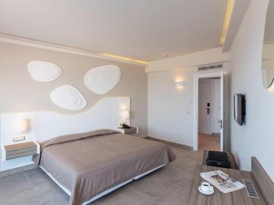 Camera d'hotel moderna con letto matrimoniale, arte da parete e scrivania con tazze da caffè.