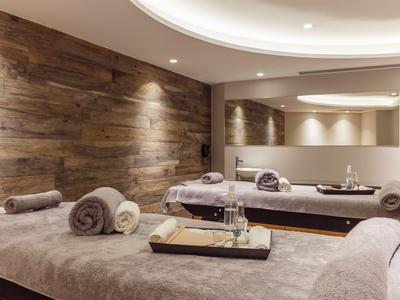 Modern eingerichteter Wellnessraum mit Holzwand und drei Massagebetten.