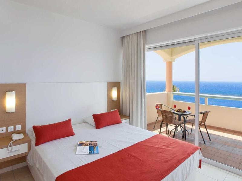 Camera d'hotel luminosa con letto matrimoniale e balcone con vista mare.