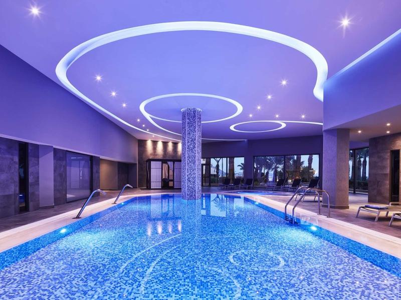 Piscina interna con illuminazione blu e design moderno del soffitto in un hotel di lusso.