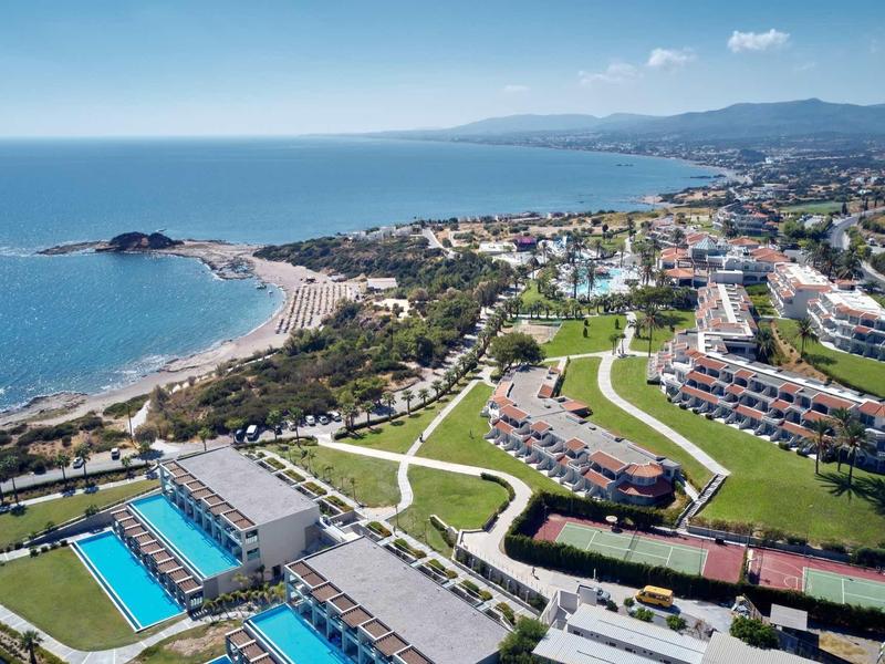 Resort costiero con piscine, prati e edifici con vista sul mare.