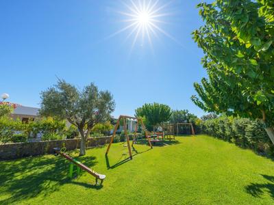 Zonnige speeltuin met schommels en groen gras in een tuin bij hotel