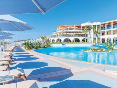 Modern hotel pool with loungers and umbrellas on a sunny day.