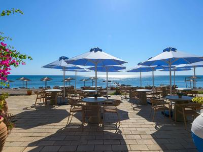 Terrace with tables and parasols overlooking the sea under a clear sky.