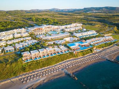 Luchtfoto van een groot resort met meerdere gebouwen, zwembaden en een strand aan de kust.