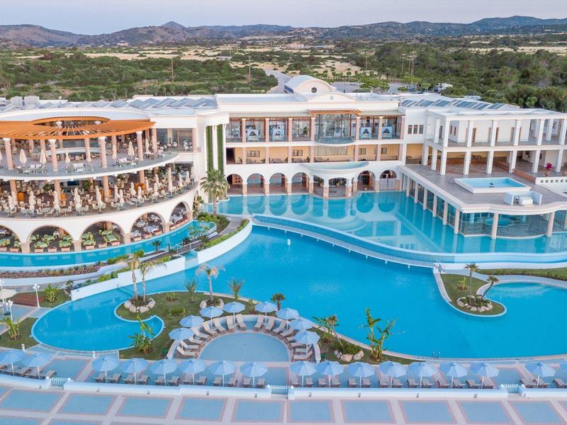 Groot luxe hotel met meerdere zwembaden omgeven door ligbedden en terrassen.