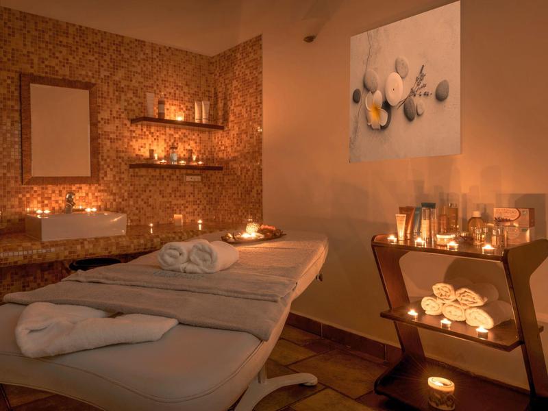 Gezellige spa kamer met massagetafel, kaarsen, handdoeken en warme sfeerverlichting.