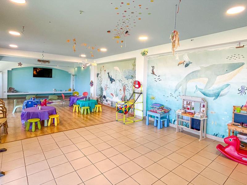 Heldere en kleurrijke kinderspeelkamer met tafels, stoelen en speelgoed in een hotel.