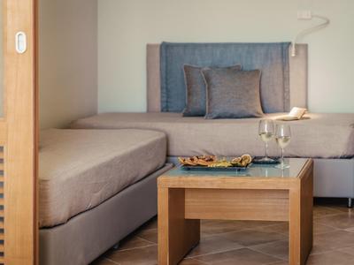 Modernes Hotelzimmer mit zwei Einzelbetten, grauer Bettwäsche und einem kleinen Couchtisch.