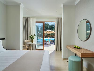 Hotelzimmer mit Blick auf Pool und Terrasse, modern eingerichtet mit Bett, Schreibtisch und Spiegel.
