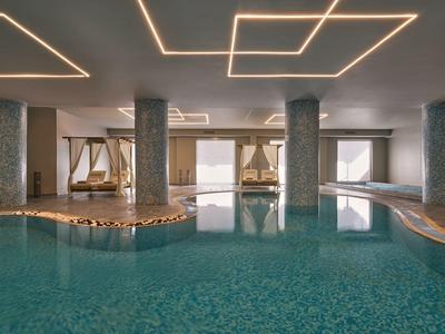 Innenpool mit Wasser und entspannenden Liegebetten in einer modernen Hotelanlage.