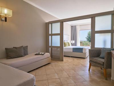 Helles Hotelzimmer mit Lounge, Schiebetüren und Balkon mit Meerblick.