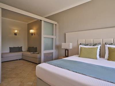 Modernes Hotelzimmer mit großem Bett und angrenzendem Wohnzimmer mit Sofa.