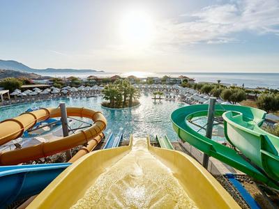 Wasserpark mit Rutschen und Poolbereich mit Blick auf das Meer bei Sonnenschein.