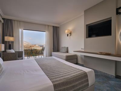 Modernes Hotelzimmer mit großem Bett, Sitzbereich und Balkon mit Aussicht.