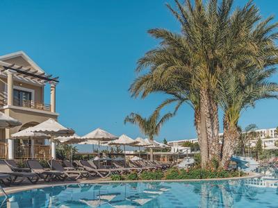 Un'area piscina lussuosa con palme e lettini davanti a un edificio alberghiero.