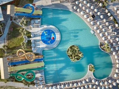 Großer Hotelpool mit Wasserrutschen, Sonnenliegen und einem Inselgarten im Wasser.