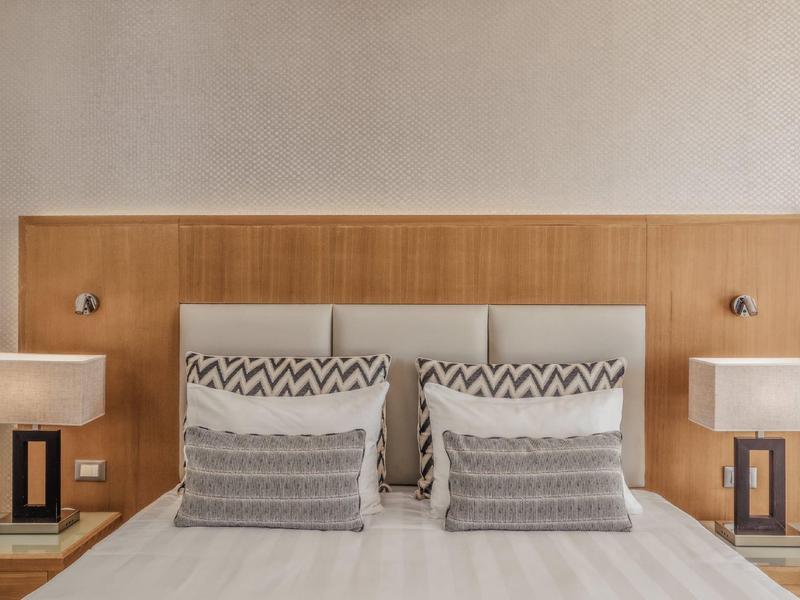 Modernes Doppelbett mit hölzernem Kopfteil und zwei Nachttischen mit Lampen