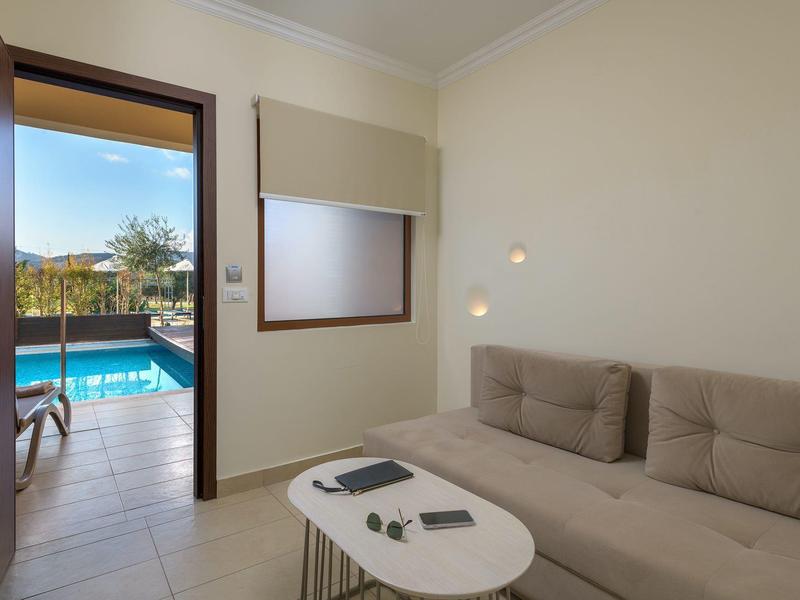 Helles Wohnzimmer mit brauem Sofa und Blick auf einen Pool im Freien.